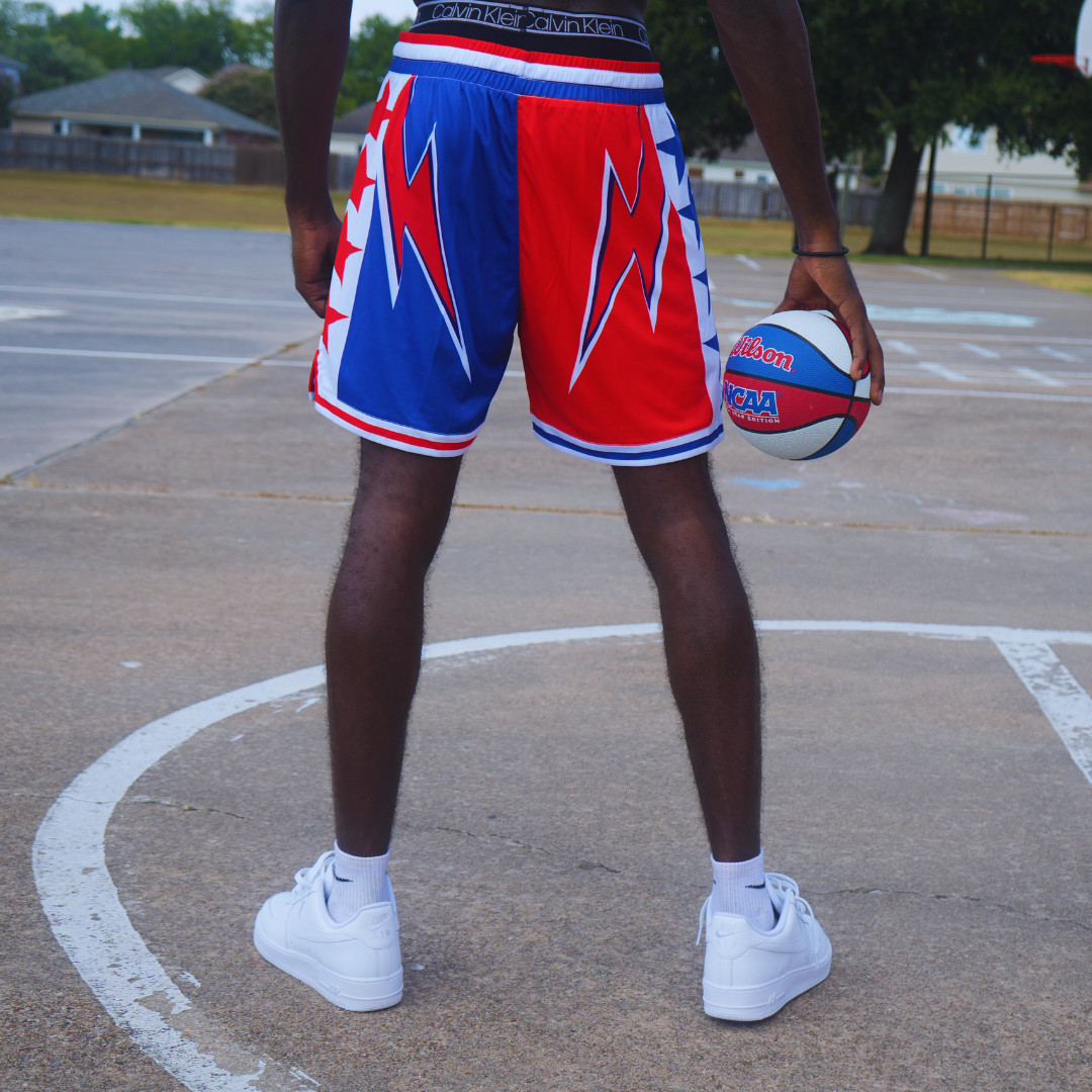 Man wearing Fire & Ice Shorts standing on basketball court holding a red, white, and blue basketball.