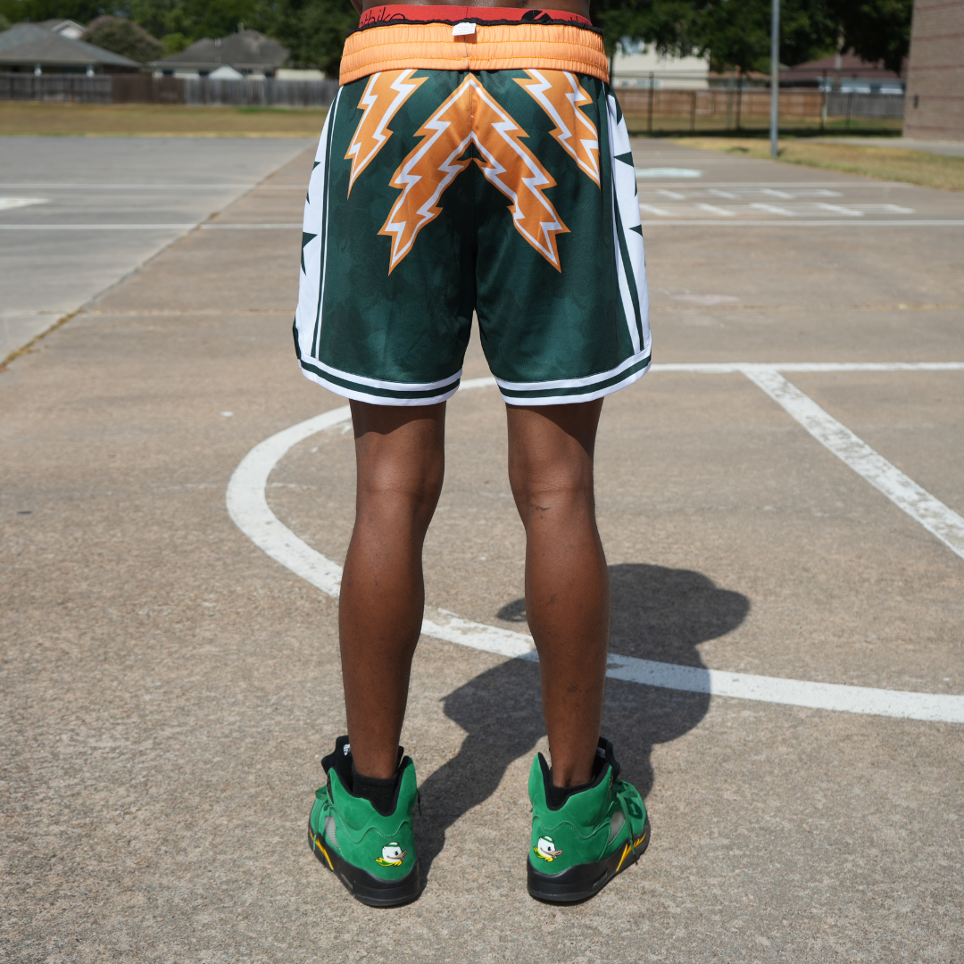 Rear view of a person wearing Emerald City Shorts with green and orange lightning design on a basketball court.