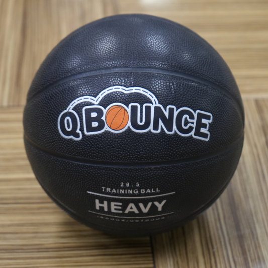 QBounce Weighted Basketball in black with textured surface for strength and precision training on wooden floor background.